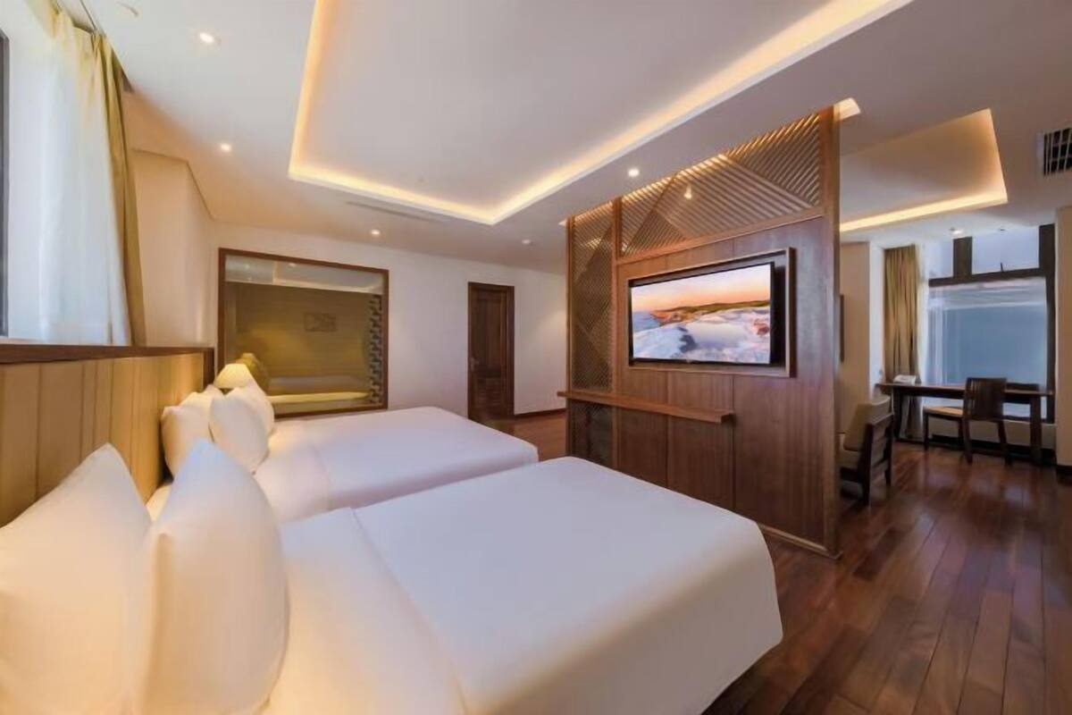 A hotel room with two beds, a TV, and a desk.