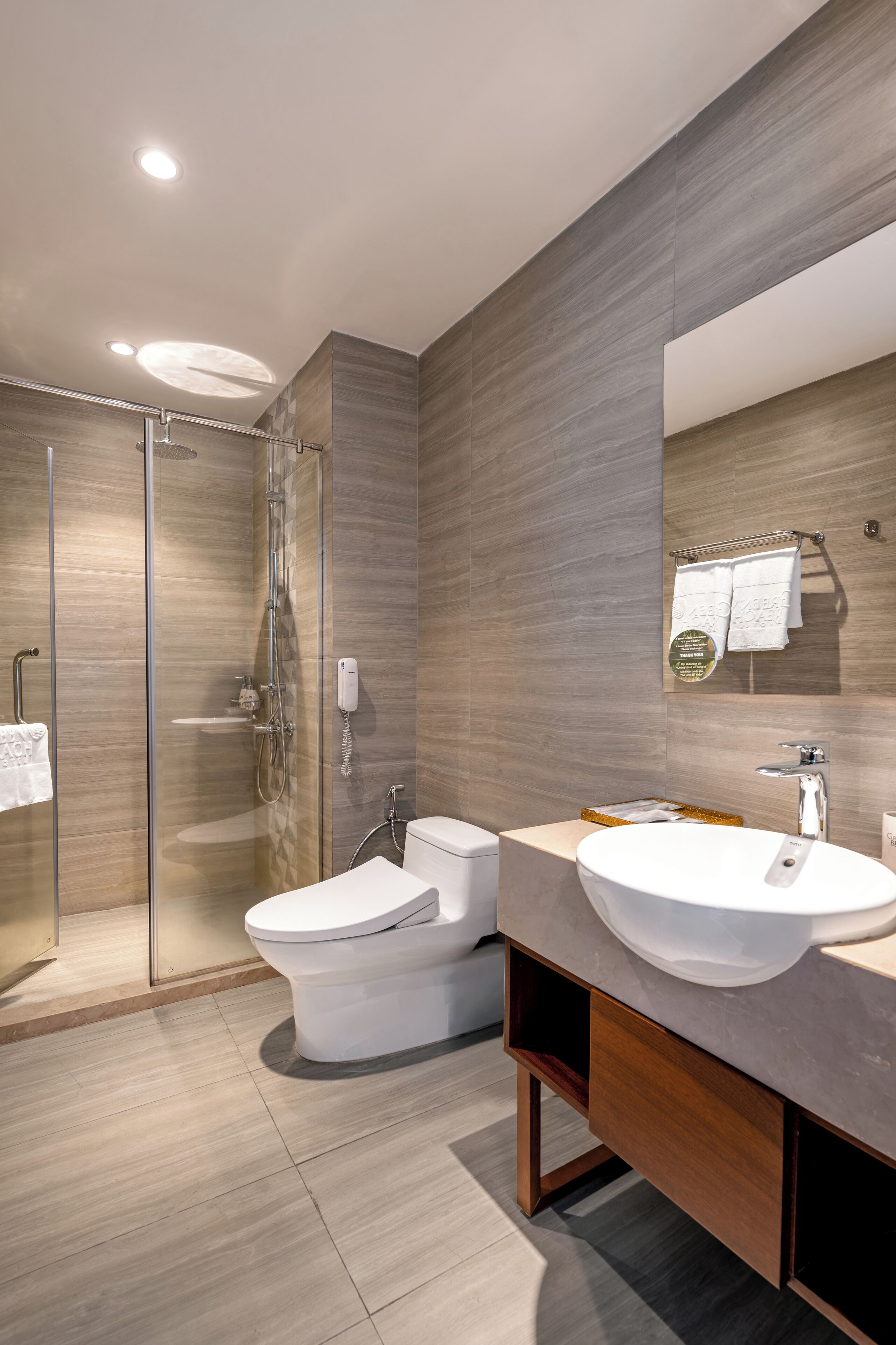 A modern bathroom with a glass-enclosed shower, a vanity with a sink, and a toilet.