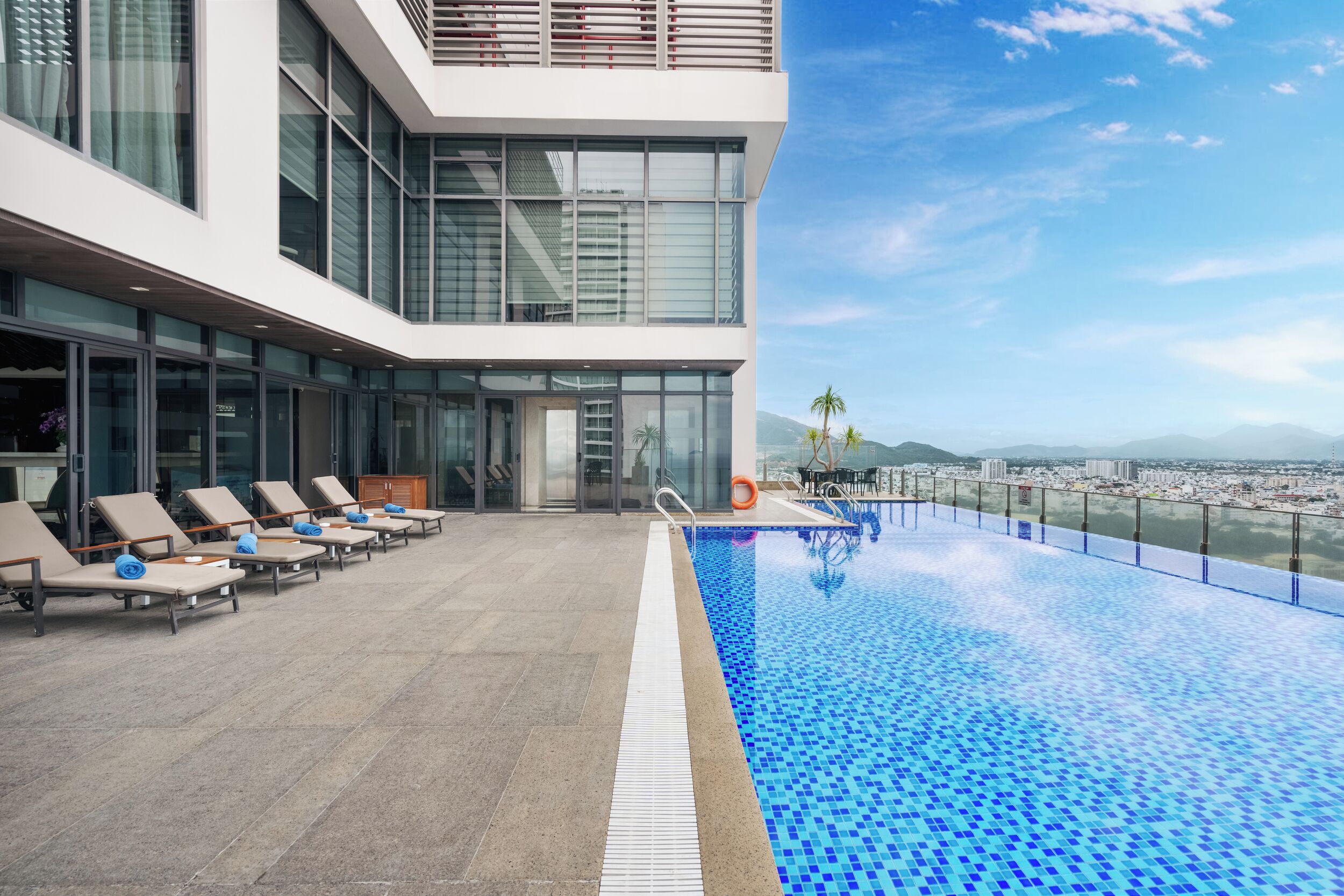 A rooftop pool with lounge chairs and a city view.