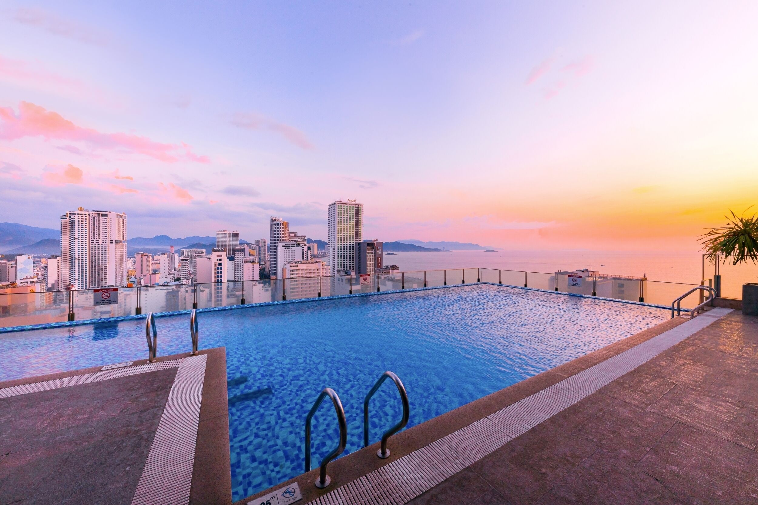 Una piscina infinita con vista al horizonte de la ciudad al atardecer.