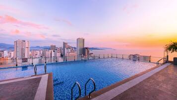 An infinity pool with a city skyline view at sunset.