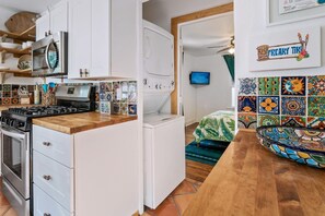 A kitchen with a stove, oven, and washing machine. There is a wooden countertop and a tiled backsplash.