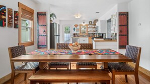 A dining area with a wooden table, four chairs, a bench, and a colorful table runner.