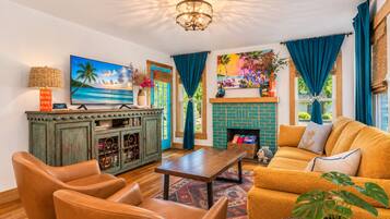 Una sala de estar con televisor, sofá, sillones, chimenea y un aparador decorativo.