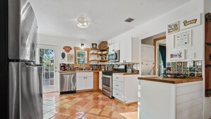 A modern kitchen with stainless steel appliances, white cabinetry, and a tiled floor.