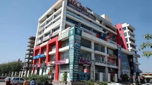 A multi-story building with various commercial establishments on the ground floor, including a cinema and several shops. - Hotel Blue Saffron (New Delhi)