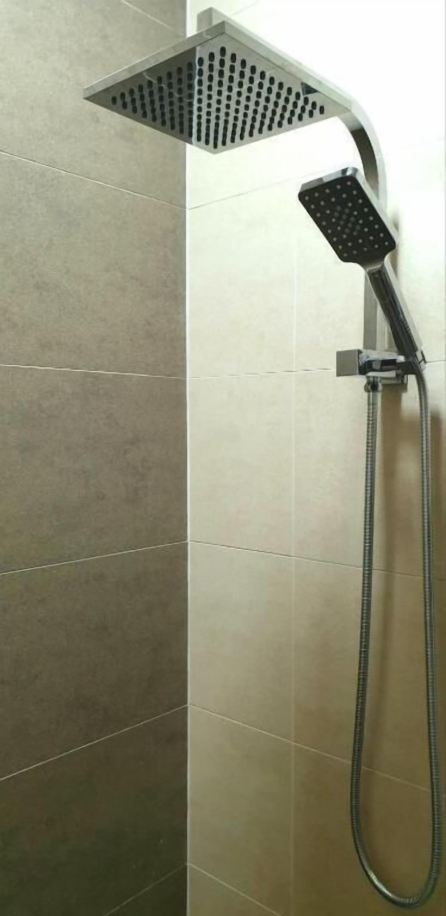 A shower with a handheld showerhead and a fixed showerhead, both mounted on a wall with a tiled surface.