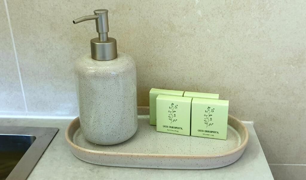 A bathroom with a soap dispenser and two green bottles labeled "GREEN ENVIRONMENTAL".