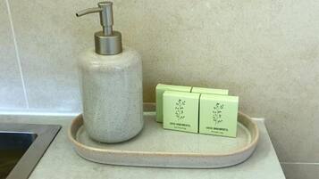 A bathroom with a soap dispenser and two green bottles labeled "GREEN ENVIRONMENTAL".