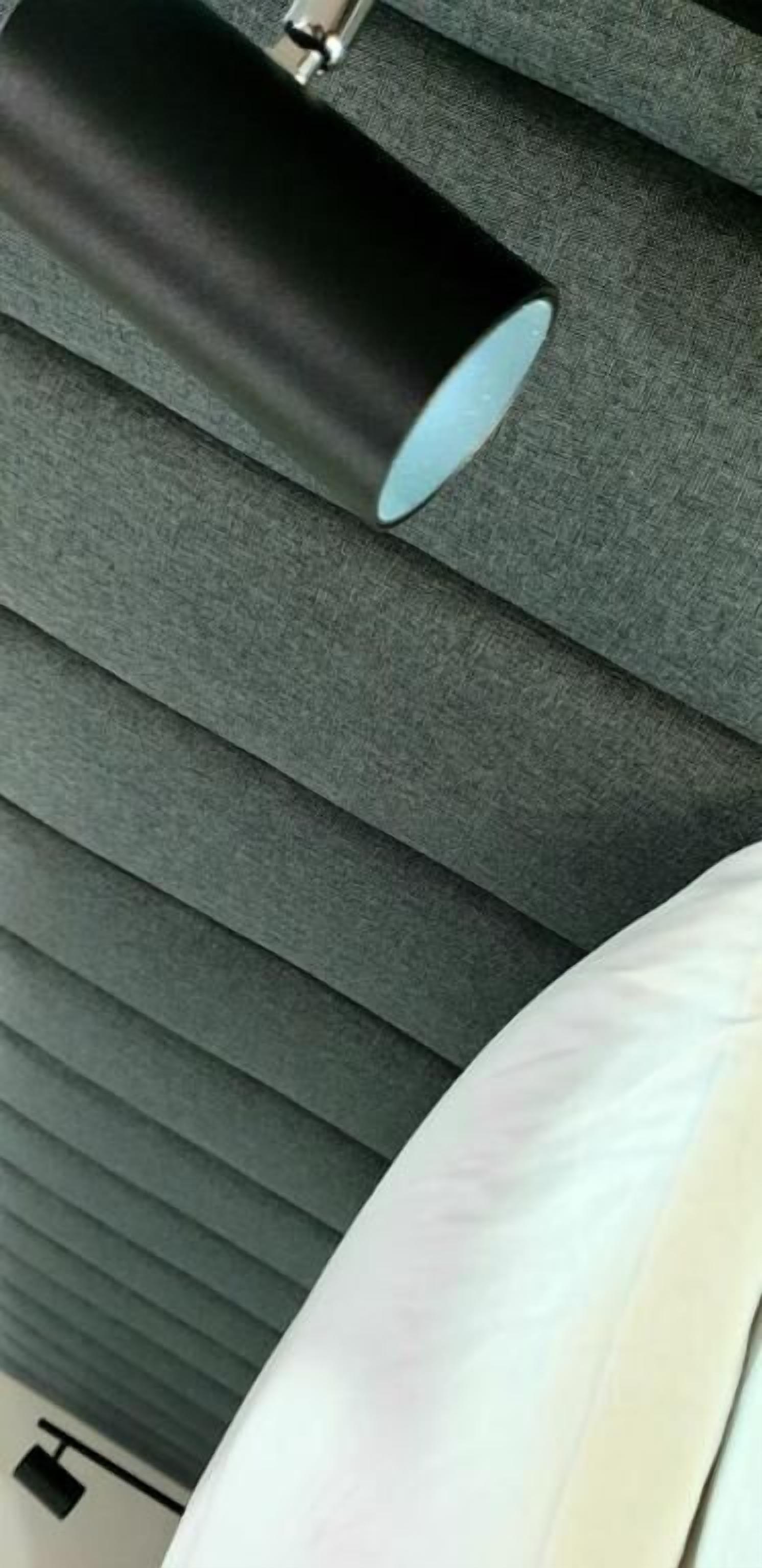 Un plafond composé de lattes horizontales, auquel est fixé un objet cylindrique, qui pourrait être un luminaire.