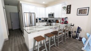 A modern kitchen with white cabinets, stainless steel appliances, and a marble countertop.
