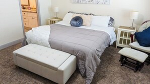 A bedroom with a bed, bedside tables, a bench, and a painting on the wall.