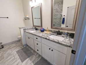 A bathroom with two sinks, a mirror, and a towel rack.