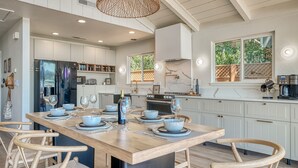 Una cocina moderna con una isla central, armarios blancos y un amplio ventanal que proporciona luz natural.