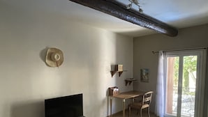 A living room with a television, a glass coffee table, a sofa, a dining table with chairs, and a sliding glass door leading to an outdoor area. - House in the heart of the village (Montagnac)