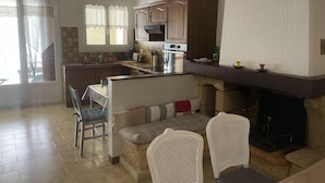 A modern kitchen with a dining area, wooden cabinets, and a fireplace. - House in the heart of the village (Montagnac)
