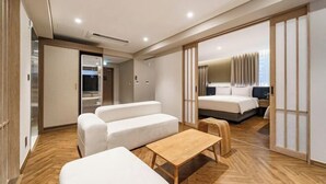A modern hotel room with a sofa set, a wooden table, and a bed with a curtain. - Hotel Foret The Spa (Busan)