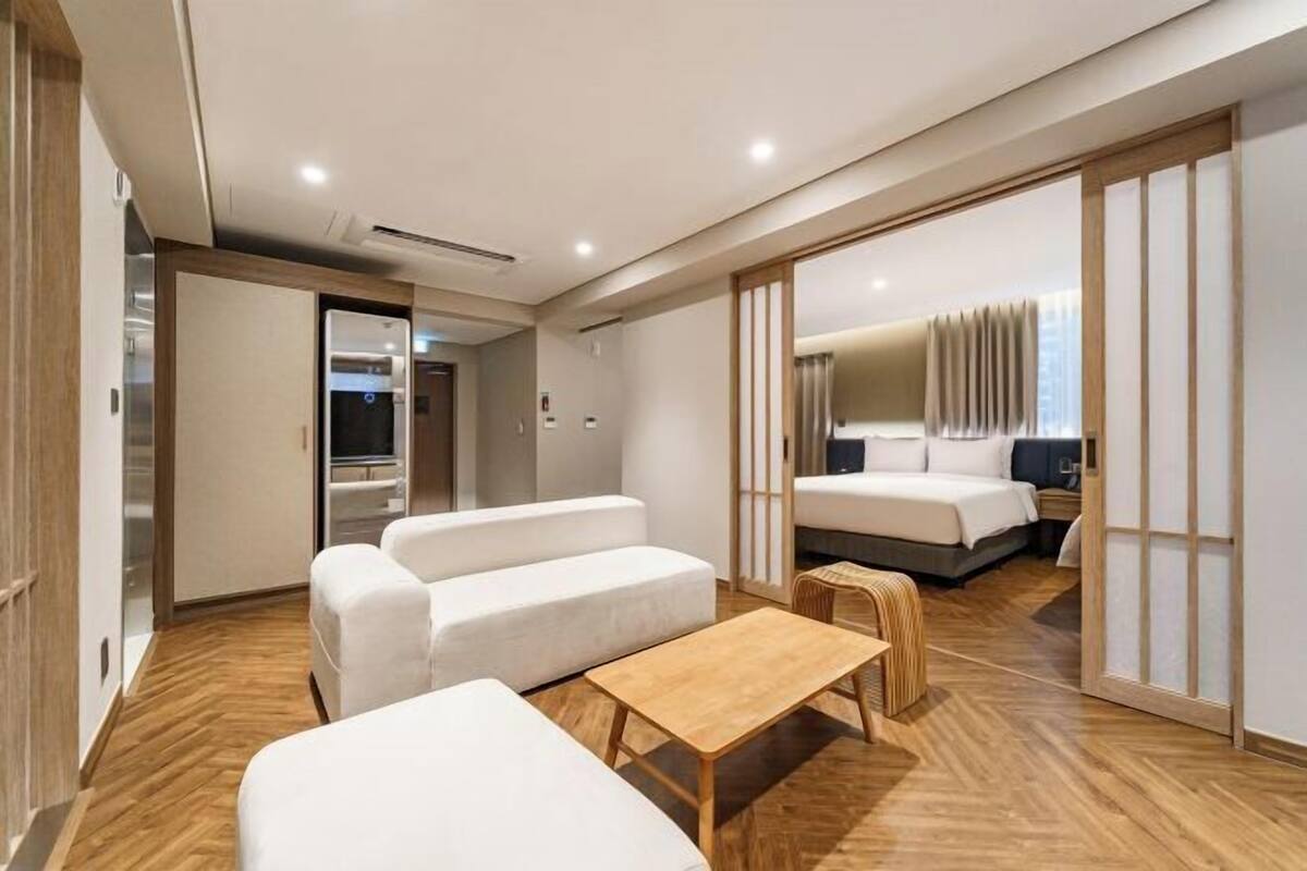 Ein modernes Hotelzimmer mit einer Sitzecke, einem Holztisch und einem Bett mit Vorhang.