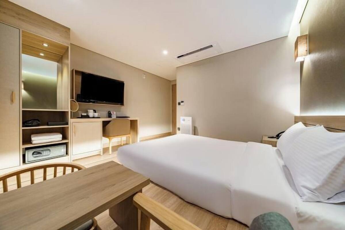 Ein Hotelzimmer mit einem Bett, einem Schreibtisch, einem Fernseher und einem Kleiderschrank.