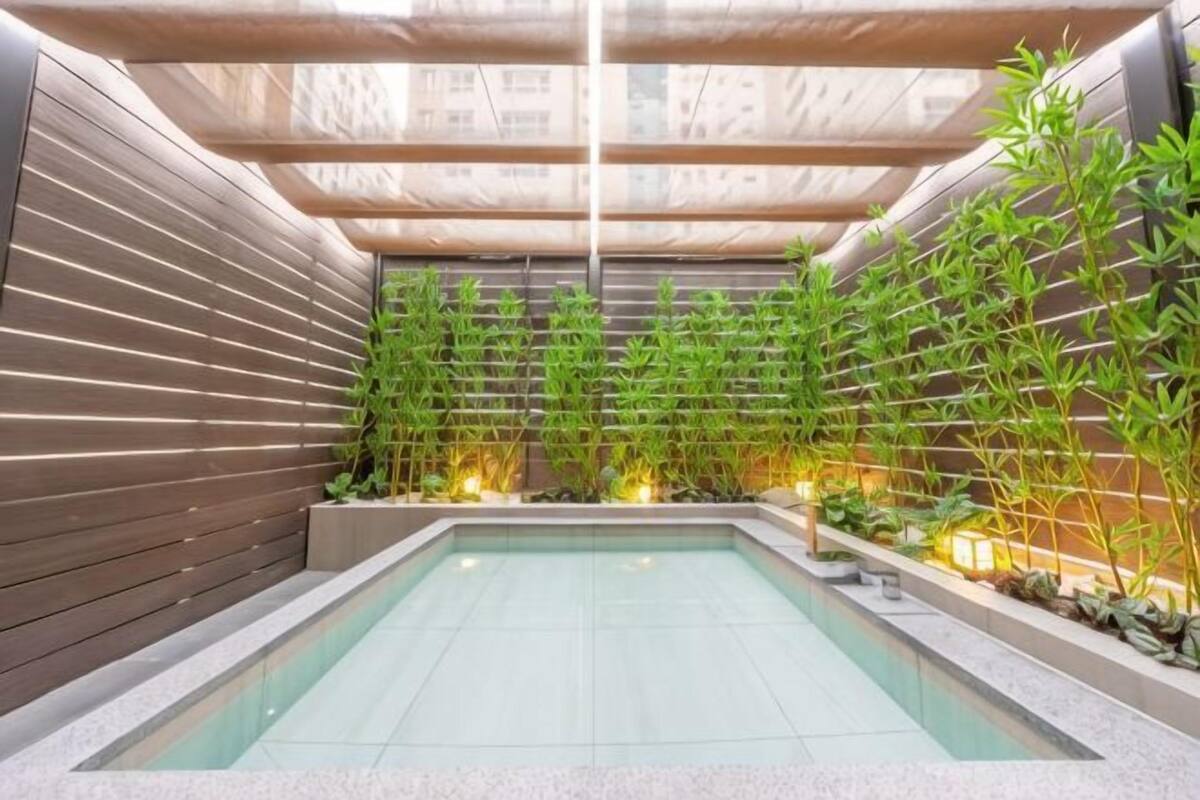 Ein moderner, überdachter Pool mit Bambuspflanzen und einer Holzwand.