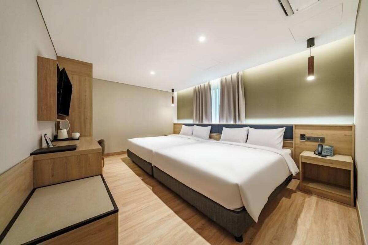 Ein modernes Hotelzimmer mit einem großen Bett, einem Nachttisch, einem Schreibtisch und einem Spiegel.