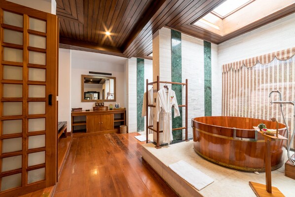 A traditional Japanese-style bathroom with a wooden bathtub, a wooden bench, and a wooden door with glass panels.