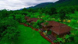Ein bungalowartiges Resort mit mehreren Holzhäusern, umgeben von üppiger Vegetation und Bergen im Hintergrund.