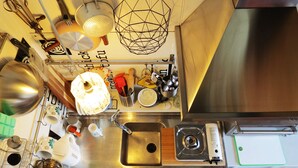 A kitchen with a stainless steel sink, a gas stove, and various utensils and appliances. - Sleep in the Clouds! The Haiku Hut... (Wentworth Falls)