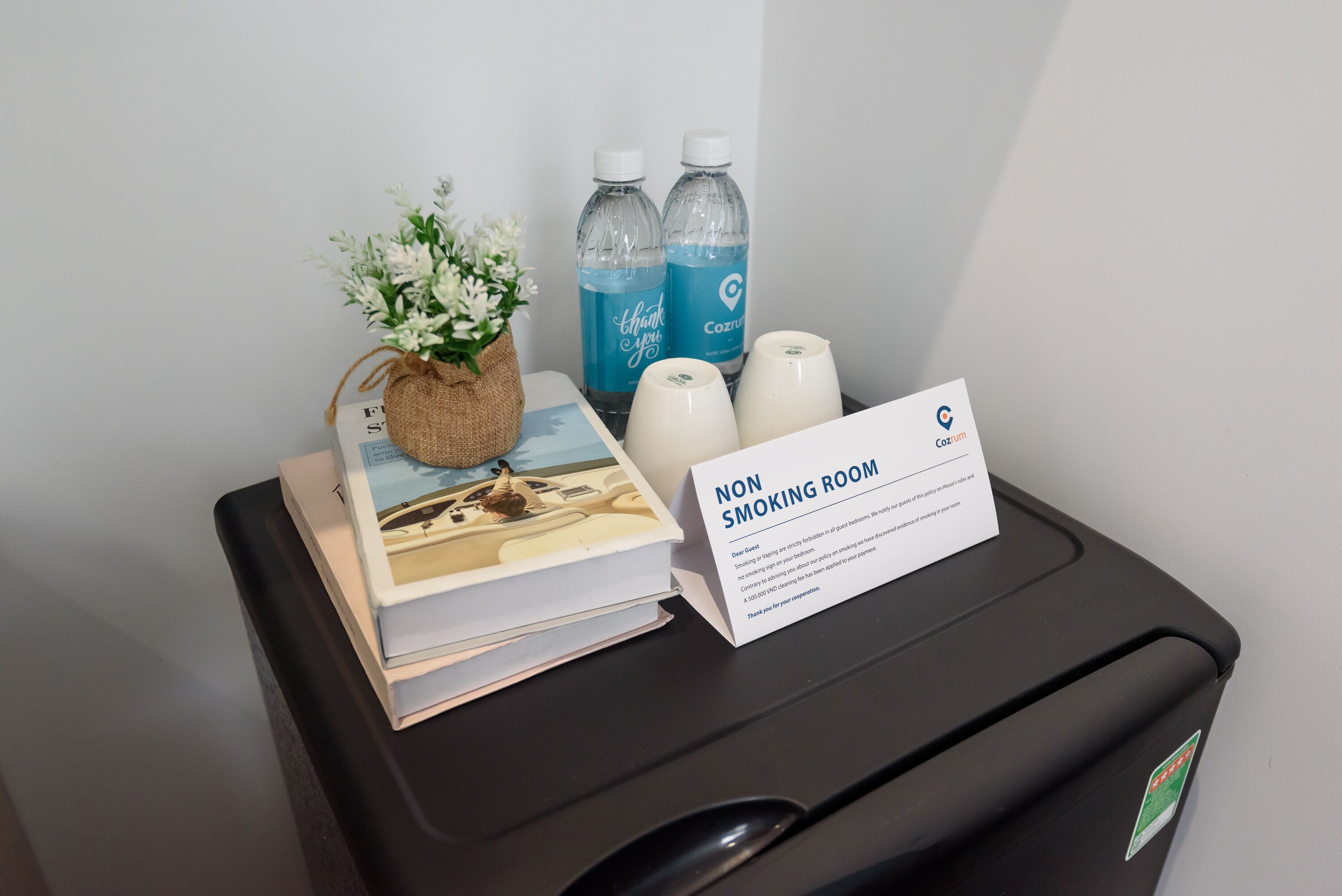 Ein Nichtraucherzimmer mit einer kleinen Pflanze, zwei Wasserflaschen und einem Buch auf einer schwarzen Oberfläche.