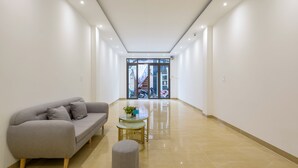 Un couloir moderne avec un canapé, un pouf et une petite table sur laquelle est posée une plante.