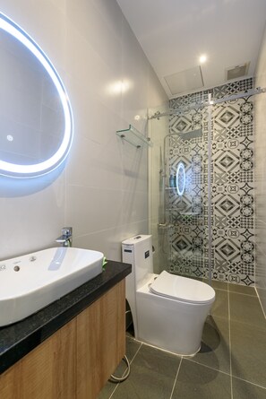 Un baño moderno con lavamanos, inodoro y cabina de ducha de vidrio.