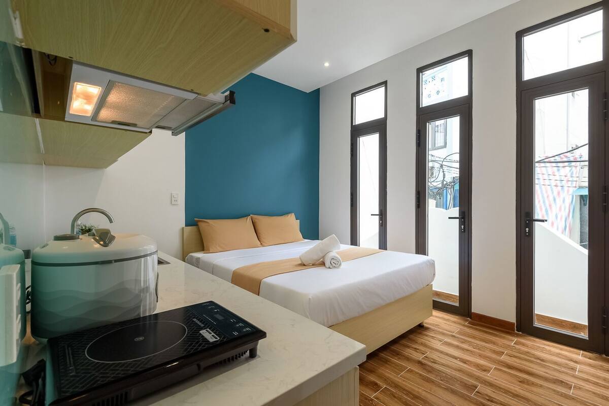Een hotelkamer met een bed, een bureau met een laptop, een wastafel en een raam.