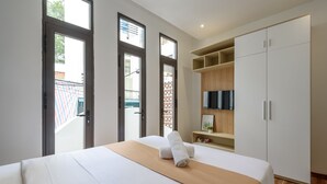 Une chambre d’hôtel avec un lit, une télévision, une armoire et un balcon offrant une vue.