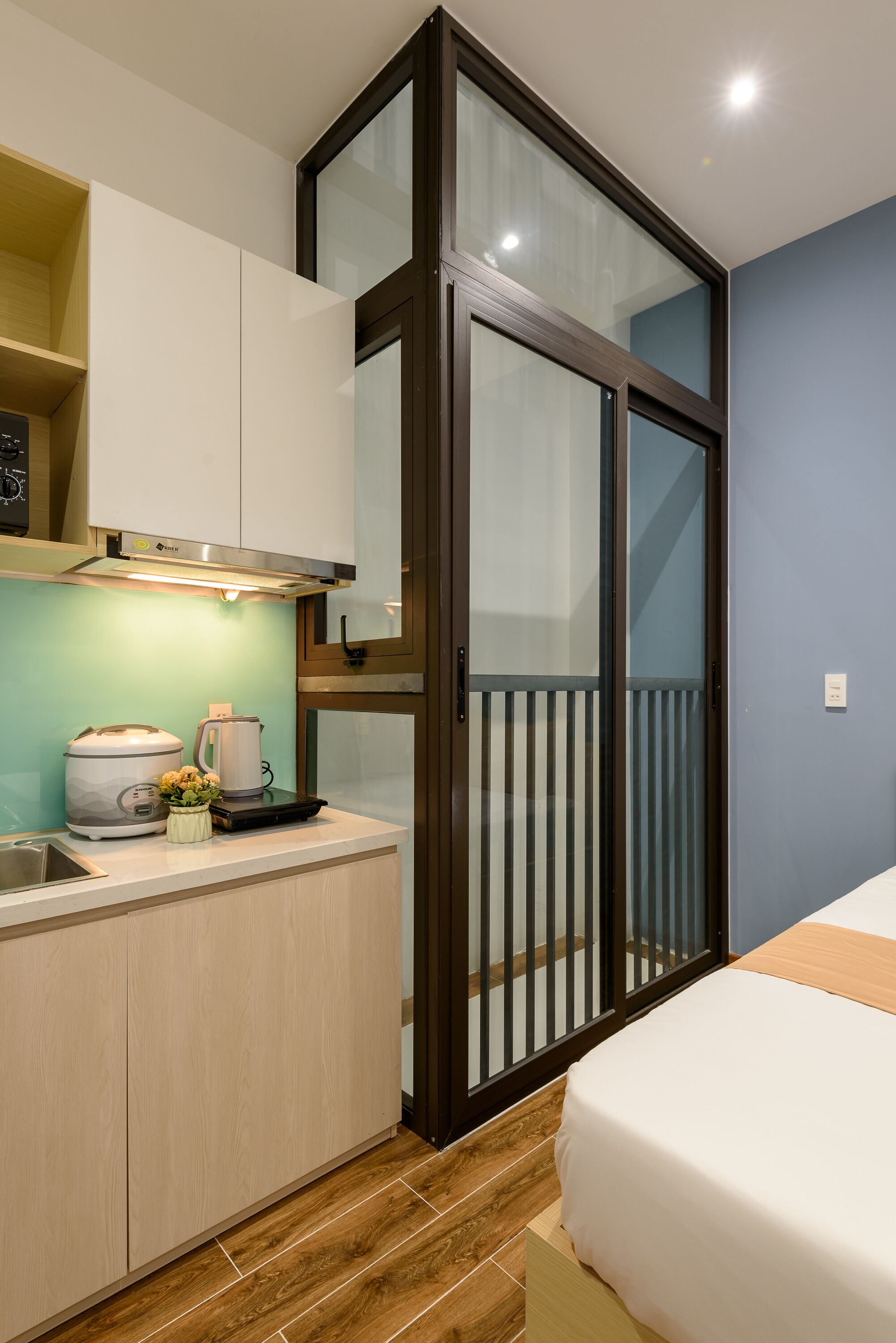 A compact kitchen with a built-in stove, a coffee maker, and a small plant on the counter.