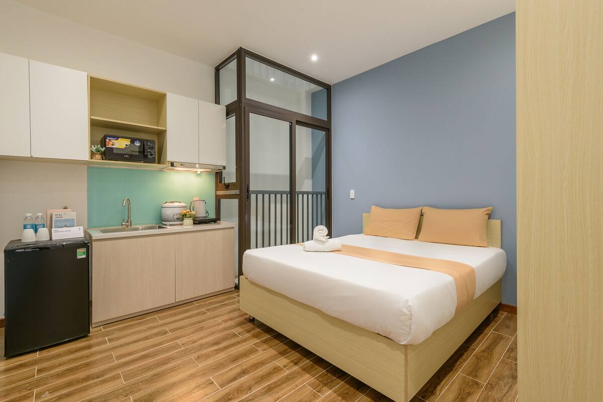 Een hotelkamer met een bed, een kleine kitchenette en uitzicht door een glazen deur.