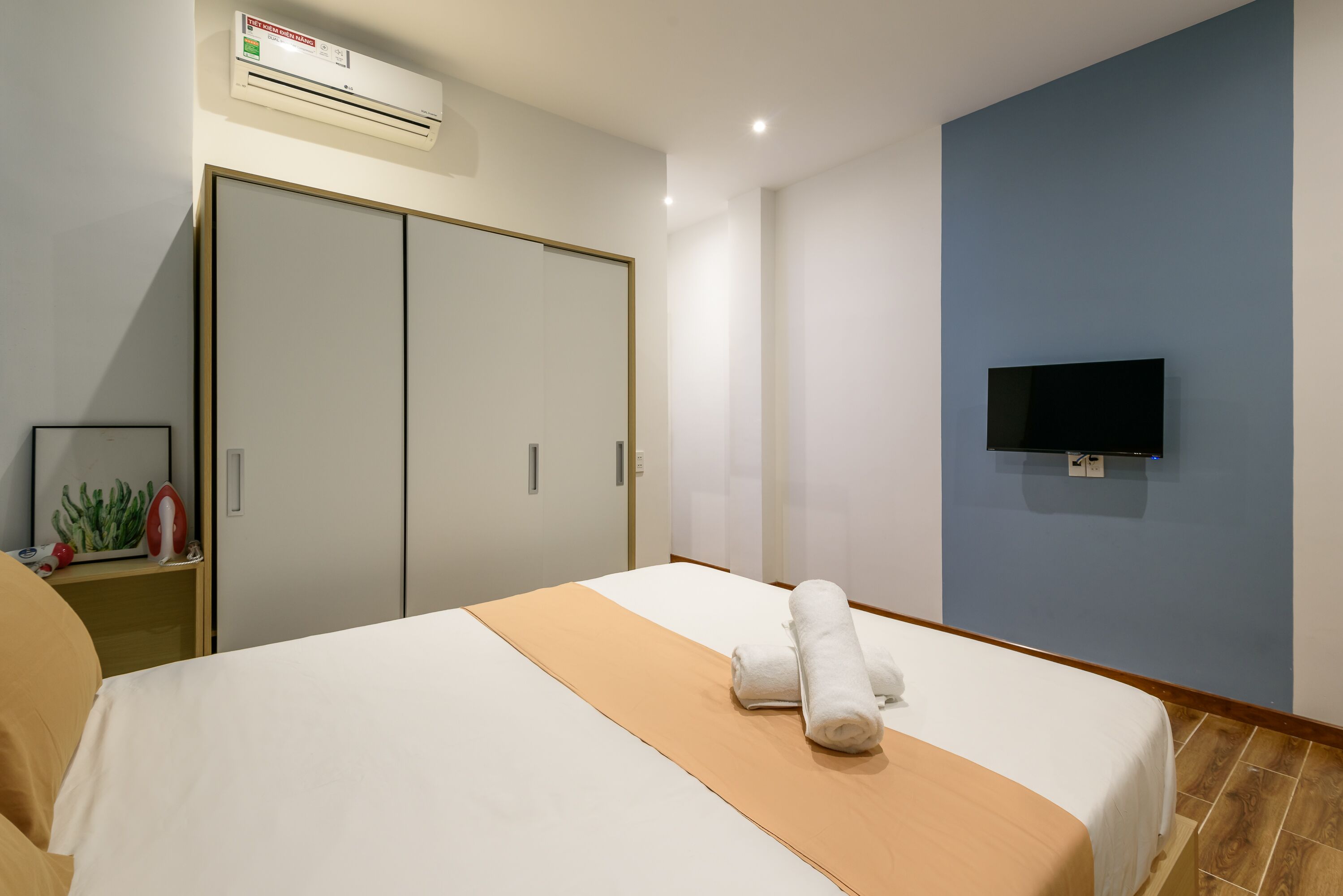 A hotel room with a bed, a TV mounted on the wall, and a wardrobe.