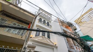 Un immeuble à plusieurs étages, doté d’éléments architecturaux décoratifs élaborés, notamment un balcon avec des balustrades ornementales et une grande fenêtre.