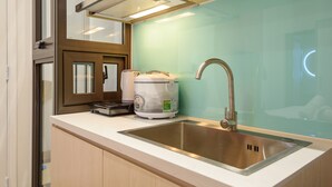 Une cuisine moderne dotée d’un évier en acier inoxydable, d’une machine à café et d’une fenêtre avec des stores.