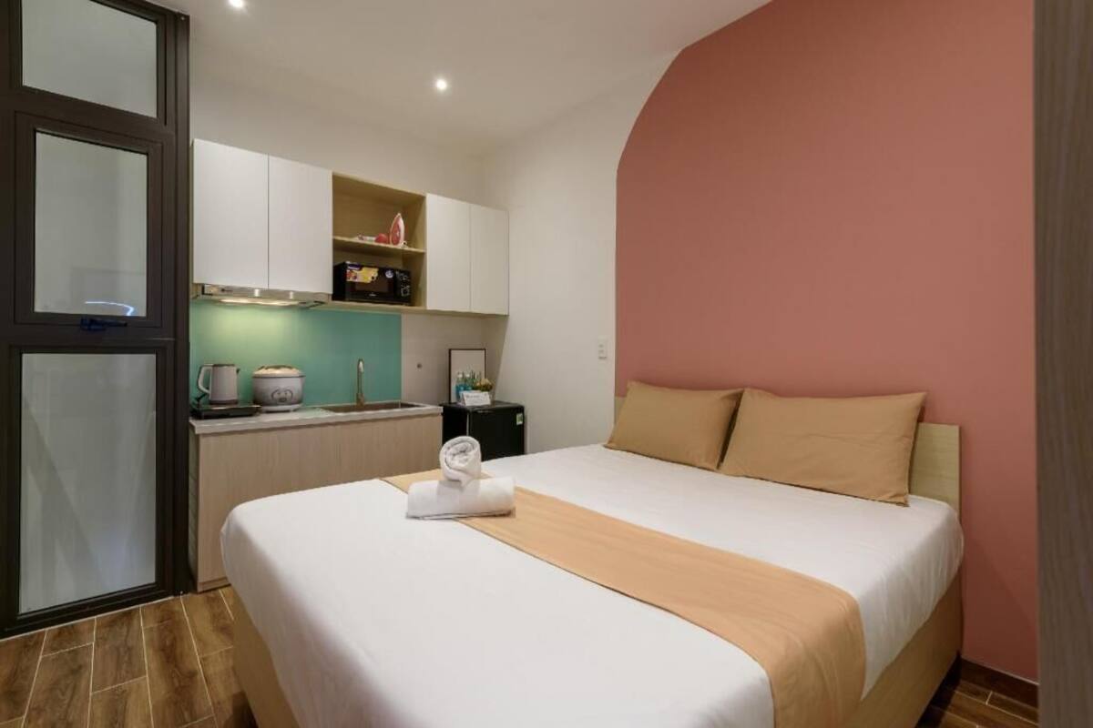 Een hotelkamer met een bed, een kitchenette, een raam en een deur.