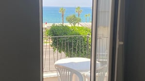 A room with a large window overlooking a balcony with a view of the sea and palm trees. - Respect Apart Hotel (Alanya)
