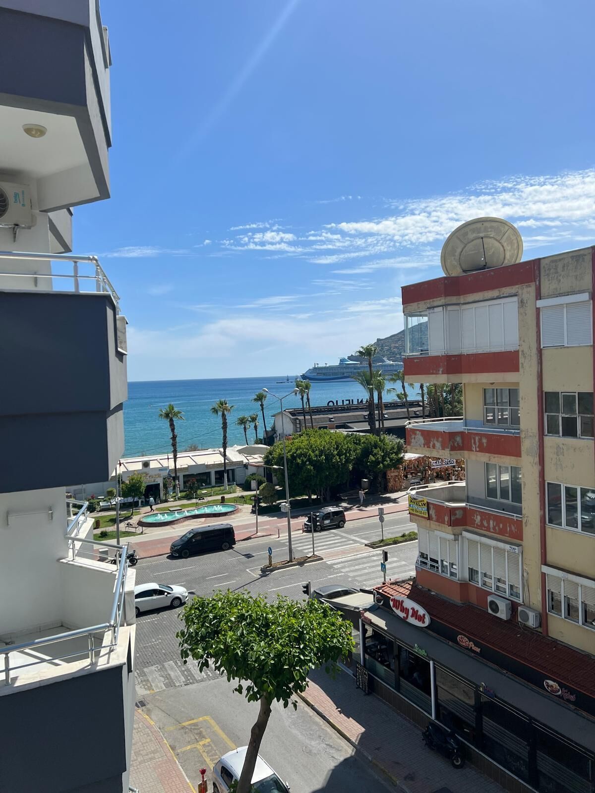 A coastal urban area with a view of the sea, a swimming pool, and a multi-story building with a satellite dish.