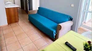 A compact living space with a kitchenette, a sofa, a table with a remote control, and a potted plant. - Respect Apart Hotel (Alanya)