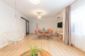 Relax in this stylish room with a round dining table, hanging chair, and potted plant.