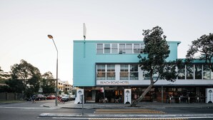 Um edifício de dois andares com uma placa que diz 'Beach Road Hotel'.