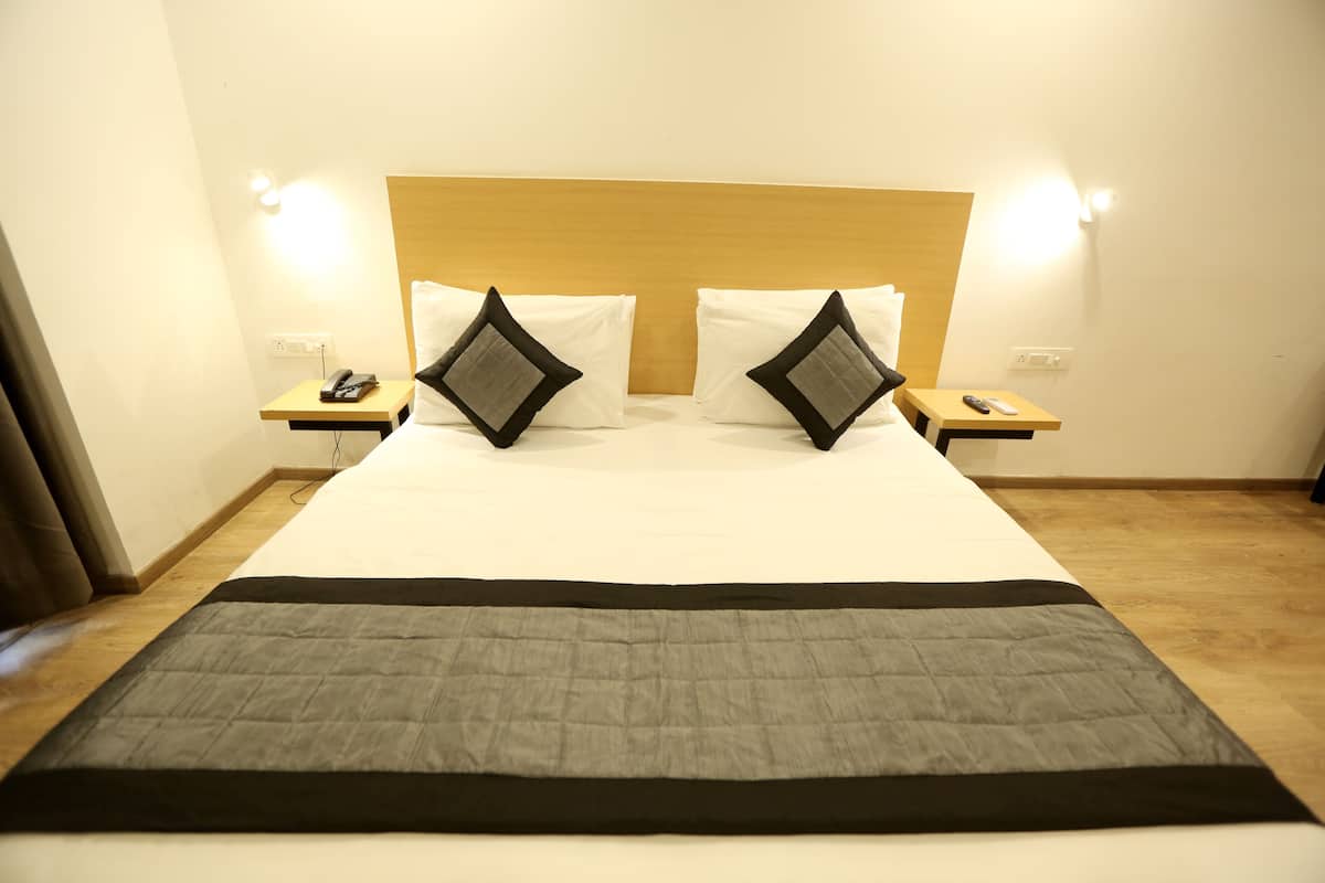 Una habitación de hotel con una cama grande, dos mesitas de noche y un cabecero.
