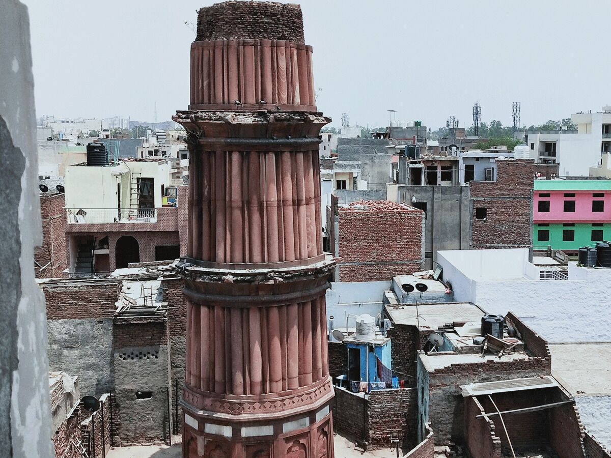 A historic tower with multiple balconies, surrounded by a densely packed urban area with various buildings.