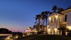 A large, well-lit building with multiple balconies and a curved driveway. - Hundert Hills (Jeju City)