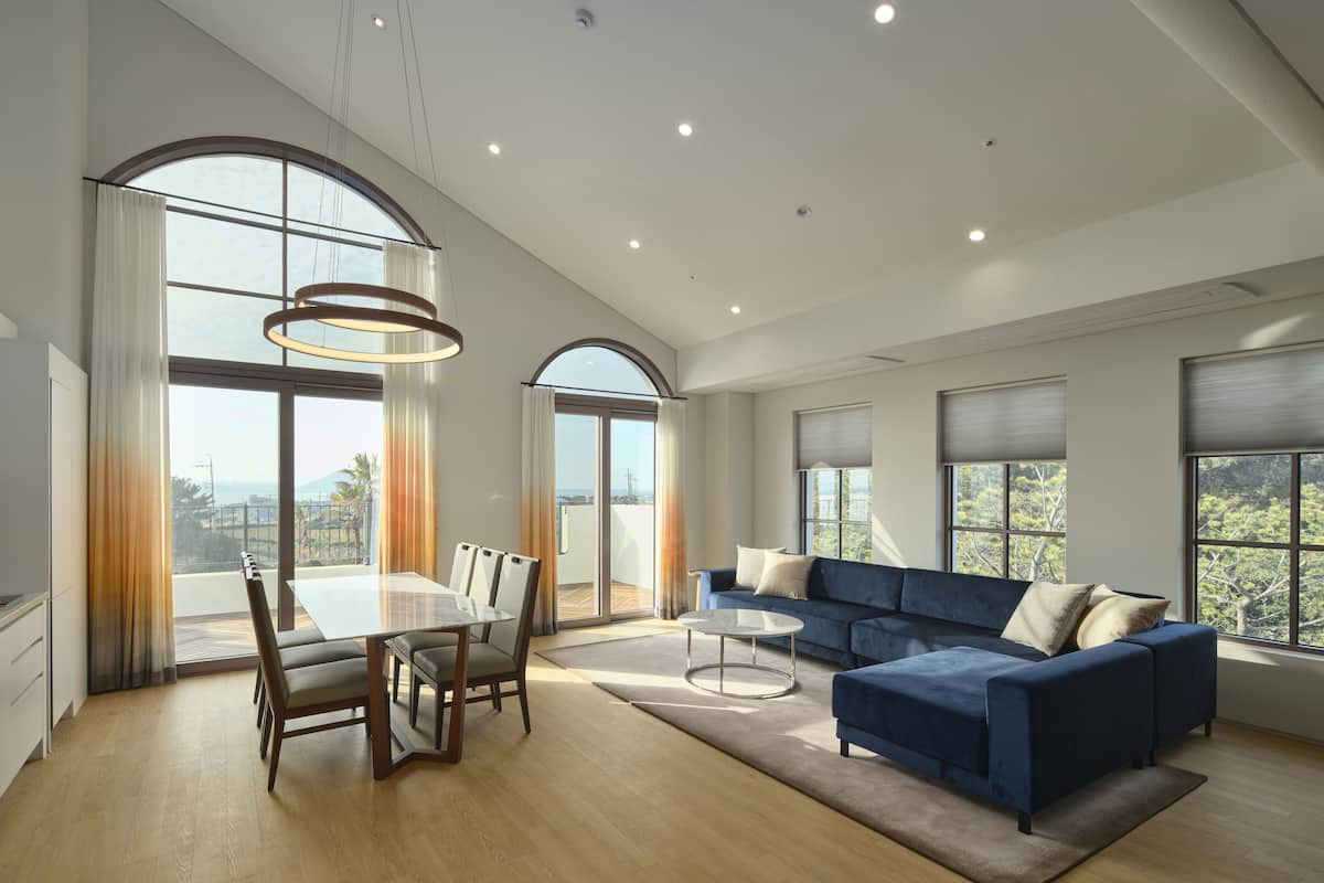A spacious living room with a dining area, large windows, and a view of the outdoors.