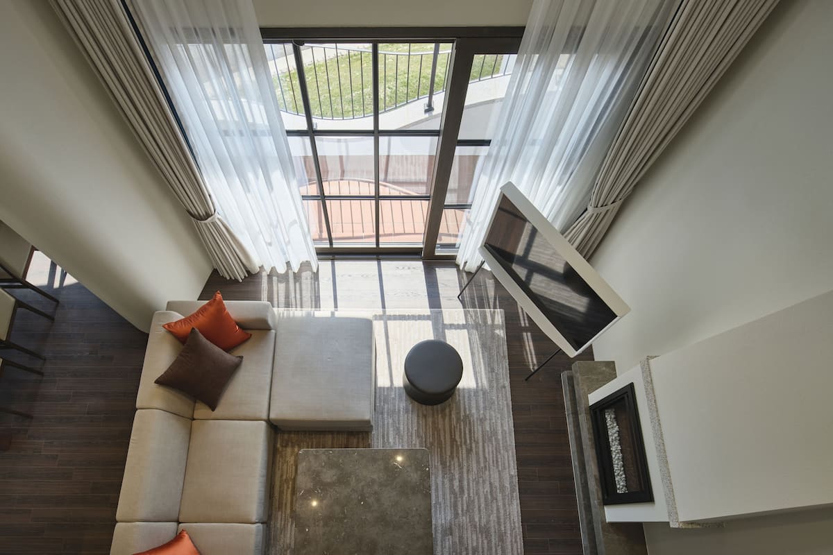 A modern interior with a sectional sofa, a flat-screen TV, and a view through large windows.