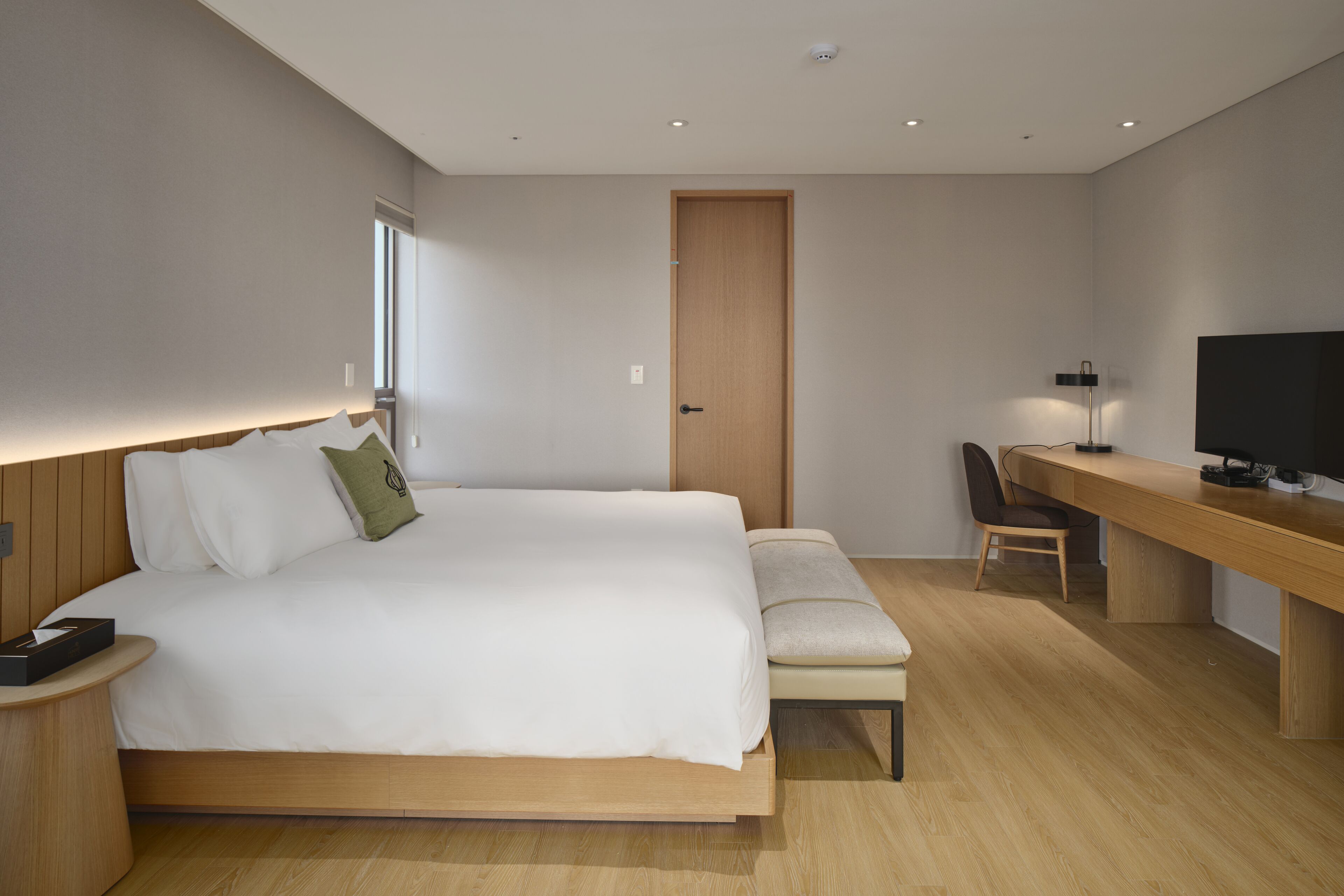 Una habitación de hotel moderna con una cama grande, una mesita de noche y un escritorio con una silla.